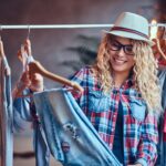 A woman chooses fashionable clothes on the coat rack.