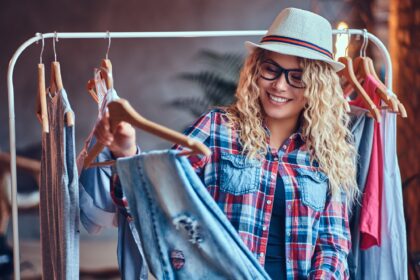 A woman chooses fashionable clothes on the coat rack.