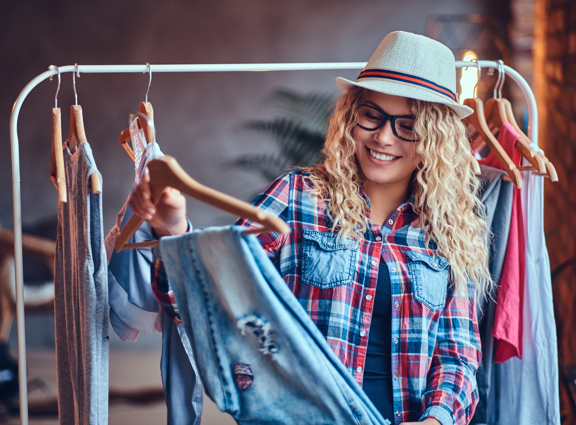 A woman chooses fashionable clothes on the coat rack.