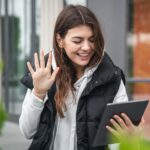 Attractive young woman uses a tablet, communicates by video call outside.