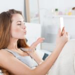 Young girl in bed taking selfie send kiss