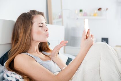 Young girl in bed taking selfie send kiss