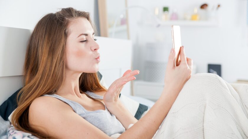 Young girl in bed taking selfie send kiss