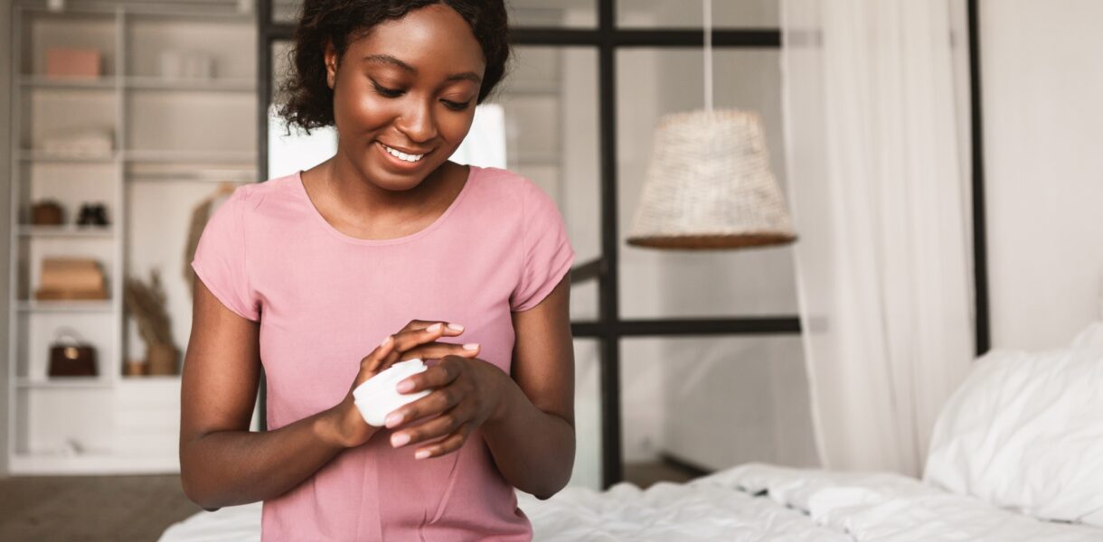 African American Lady Applying Hands Cream Moisturizing Skin In Bedroom
