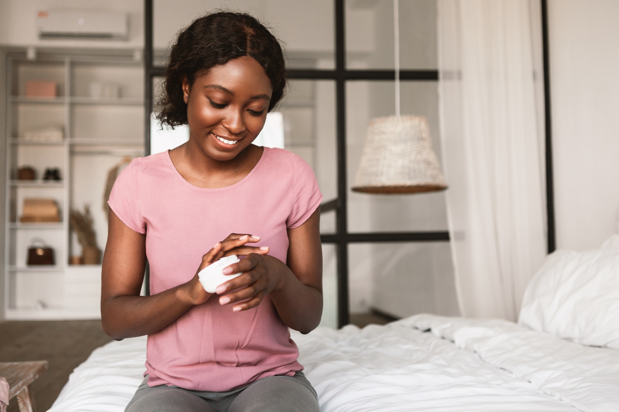African American Lady Applying Hands Cream Moisturizing Skin In Bedroom