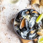 Blue mussels in wine sauce with lime and bread. Stew mussels in wine, leek and blue cheese. Seafood