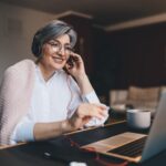 Happy mature woman with headphones and laptop at table