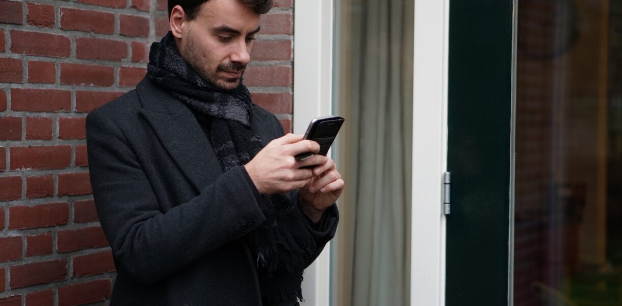 Handsome young man, texting, checking his Whatsapp on his phone.
