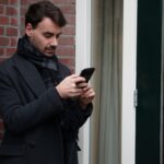 Handsome young man, texting, checking his Whatsapp on his phone.