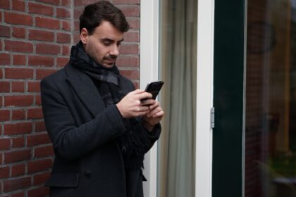 Handsome young man, texting, checking his Whatsapp on his phone.