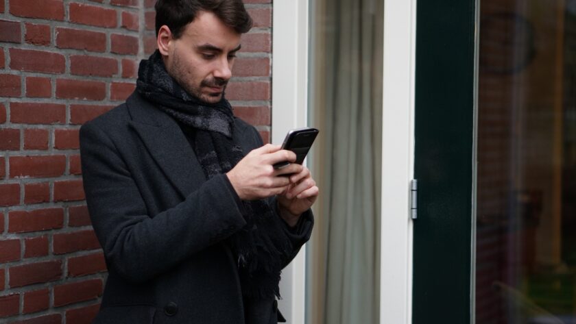 Handsome young man, texting, checking his Whatsapp on his phone.