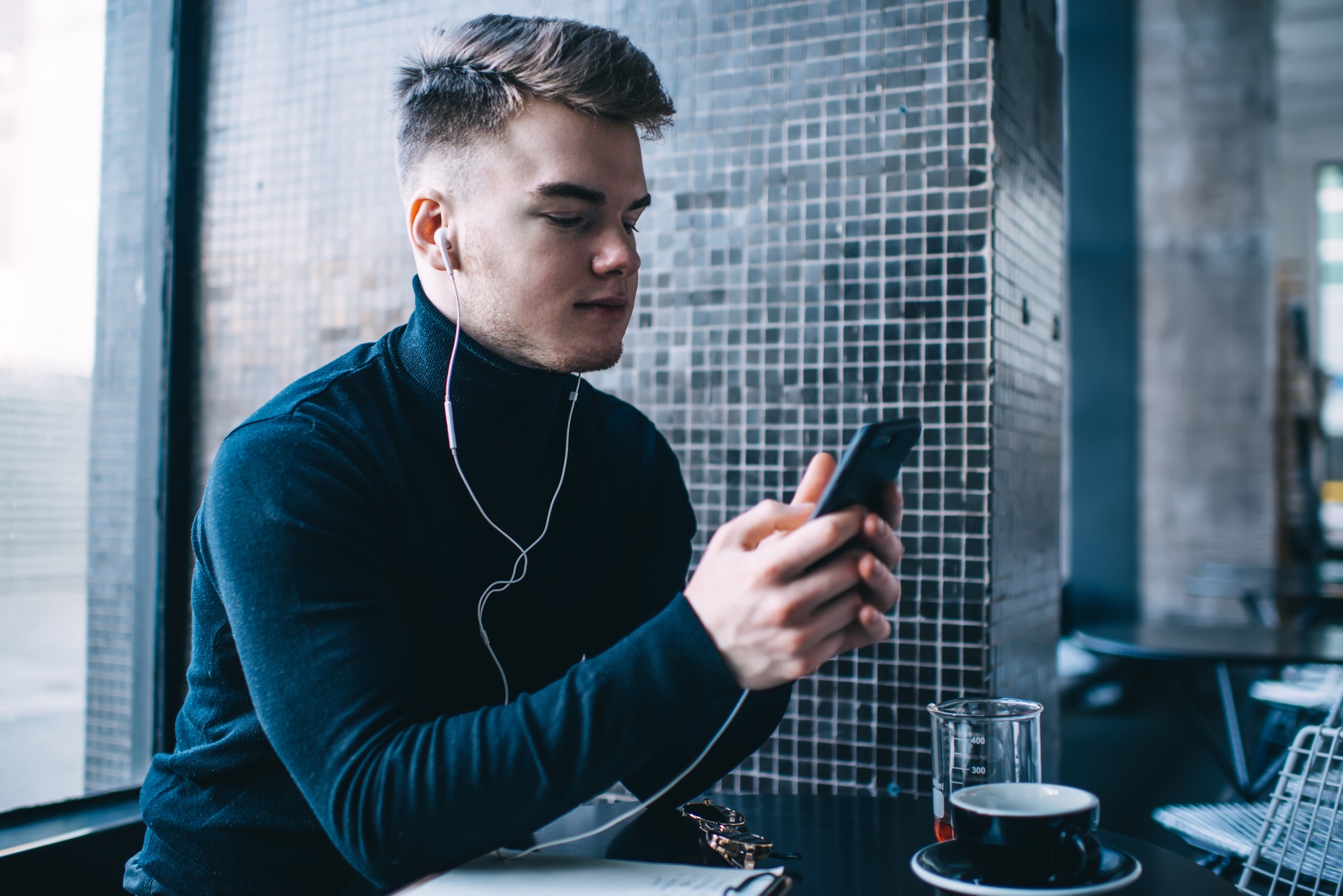 Thoughtful man text messaging in cafe