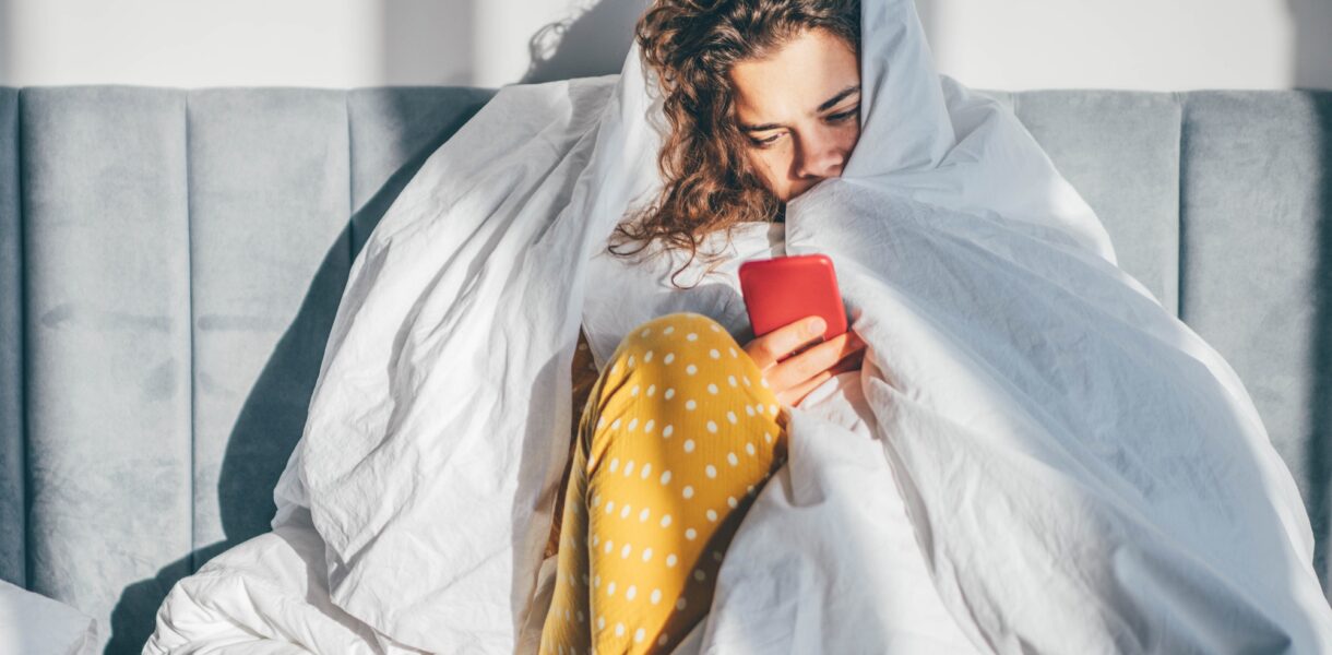 Unhappy woman with phone in a bedroom.