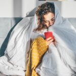 Unhappy woman with phone in a bedroom.