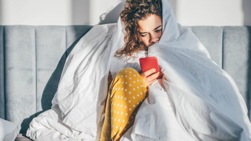Unhappy woman with phone in a bedroom.