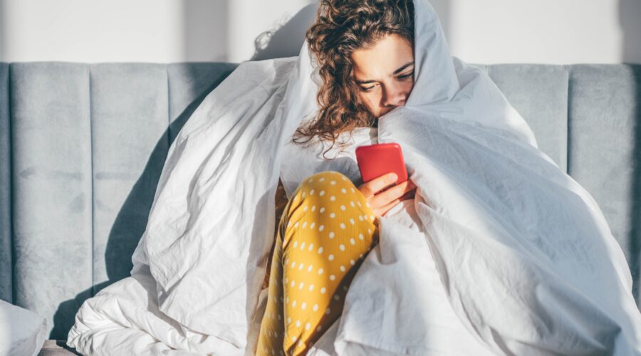 Unhappy woman with phone in a bedroom.