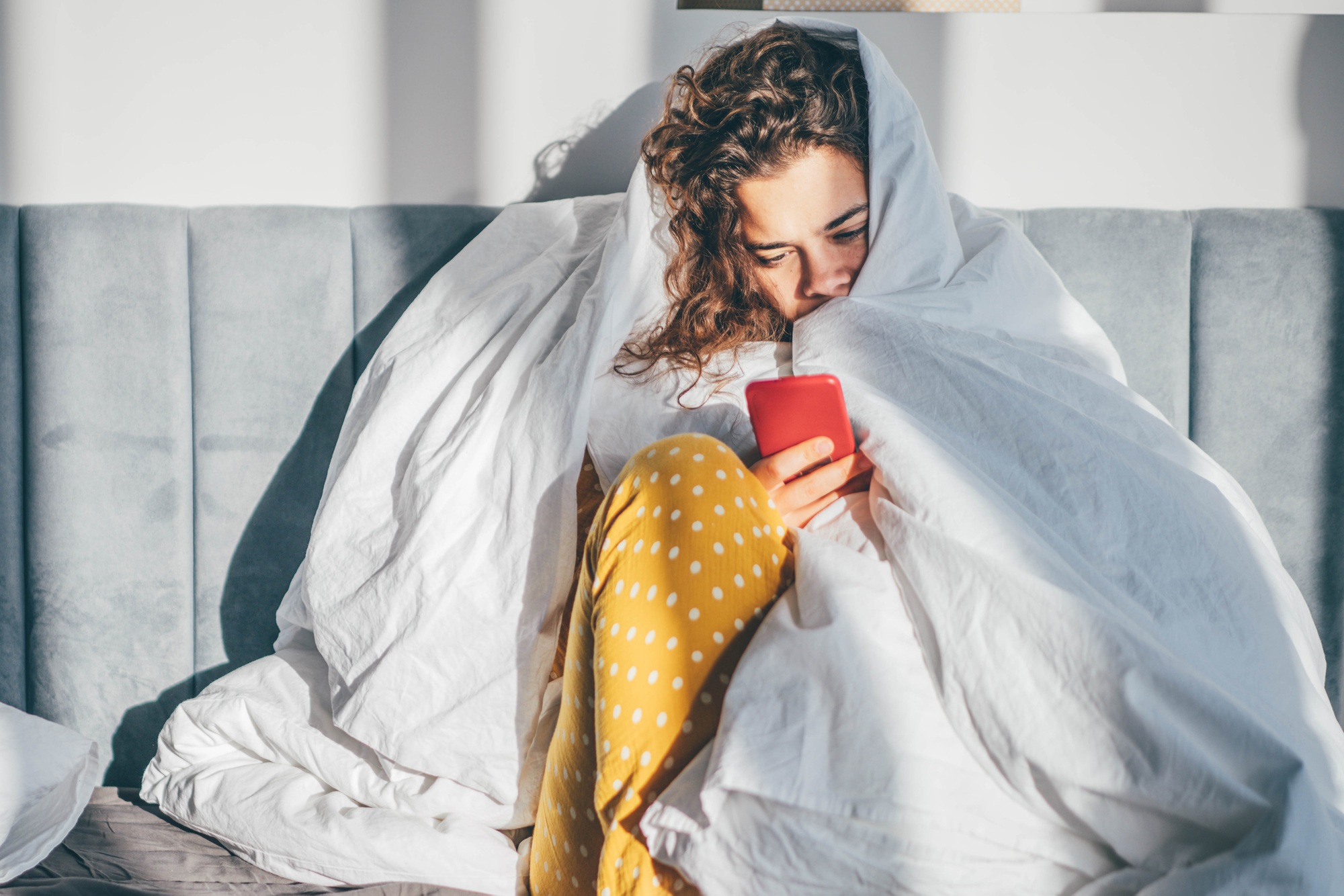 Unhappy woman with phone in a bedroom.