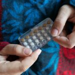women hand holding birth control pills close up